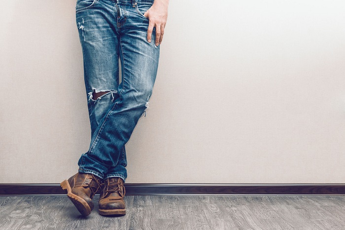 37468442 - young fashion man's legs in jeans and boots on wooden floor